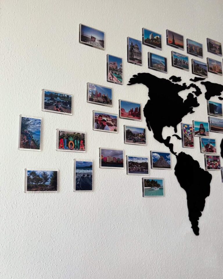 Ein Wanddisplay mit Reisefotos, die um eine schwarze Weltkartensilhouette angeordnet sind.